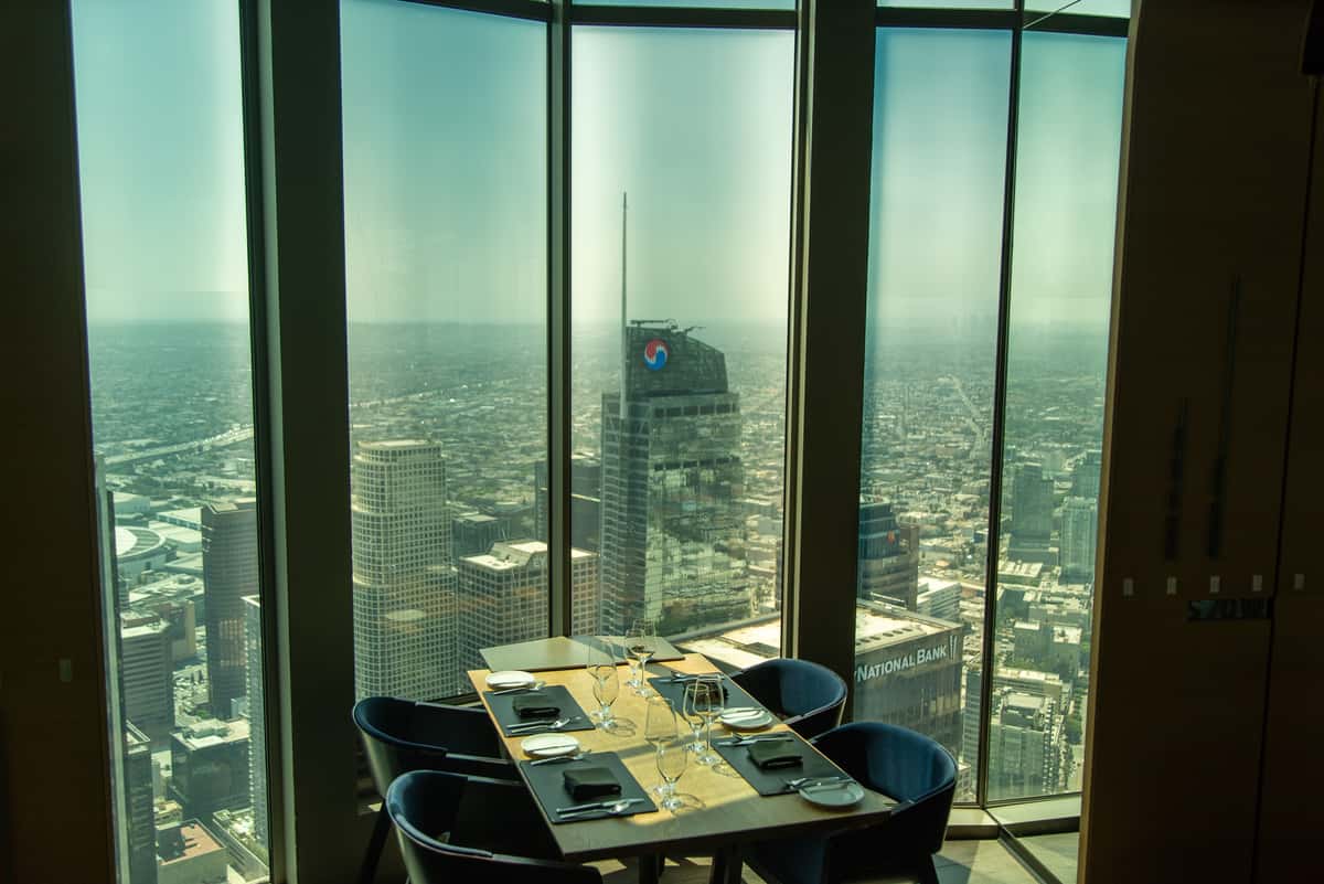 71Above dining room with 360-degree views of the Los Angeles skyline at night, featuring city lights and elegant table settings.