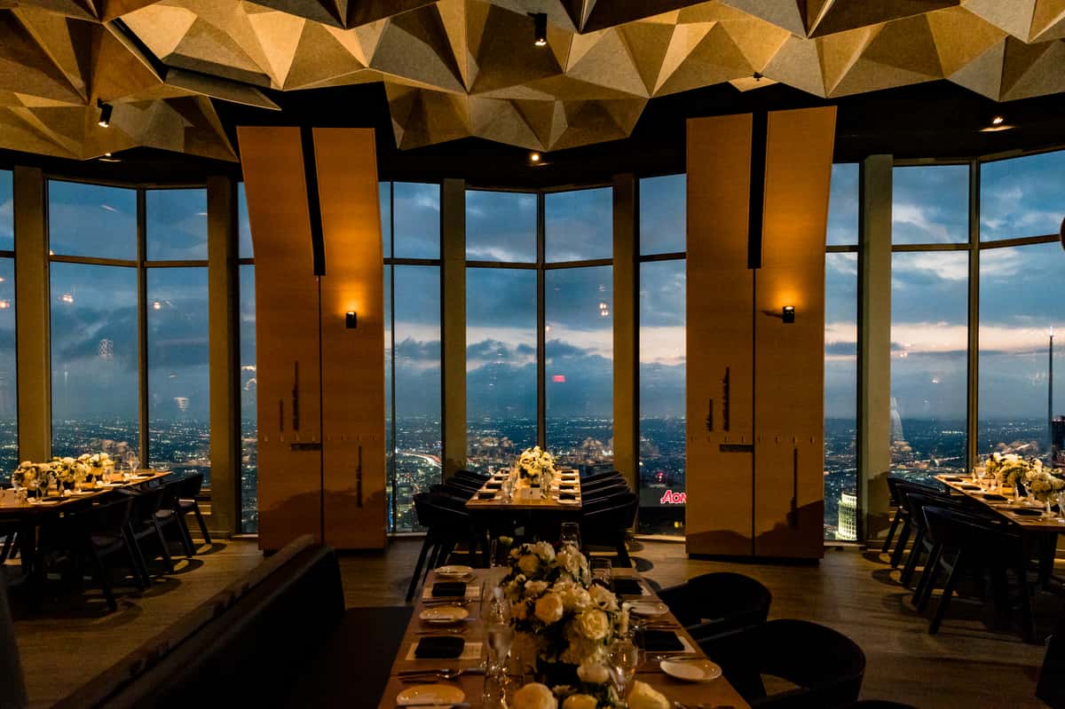 Dining room at 71Above with floor-to-ceiling windows showcasing panoramic views of the Los Angeles skyline at sunset