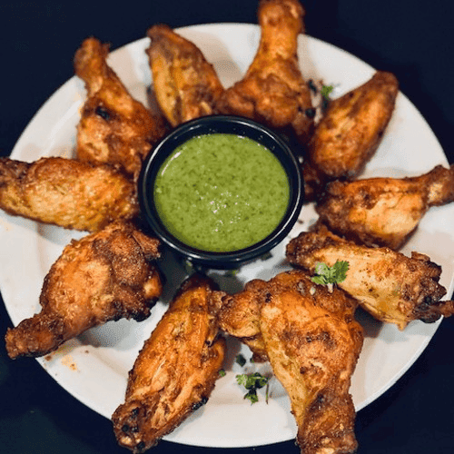 Chicken pieces on a plate with a sauce at the center