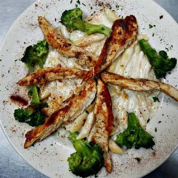 penne pasta with alfredo sauce served with broccoli and cajun chicken breast strips