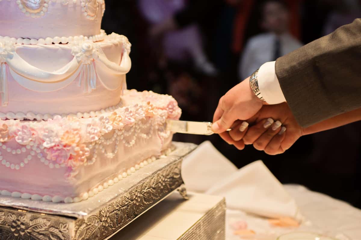 Groom and Bride Slicing Wedding Cake