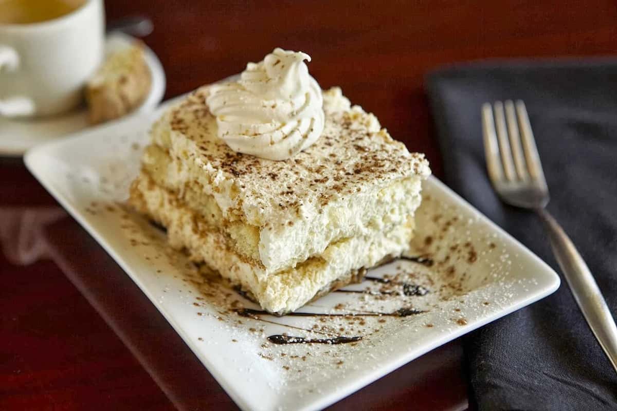 Layered tiramisu topped with whipped cream and cocoa at Positano Ristorante Italiano