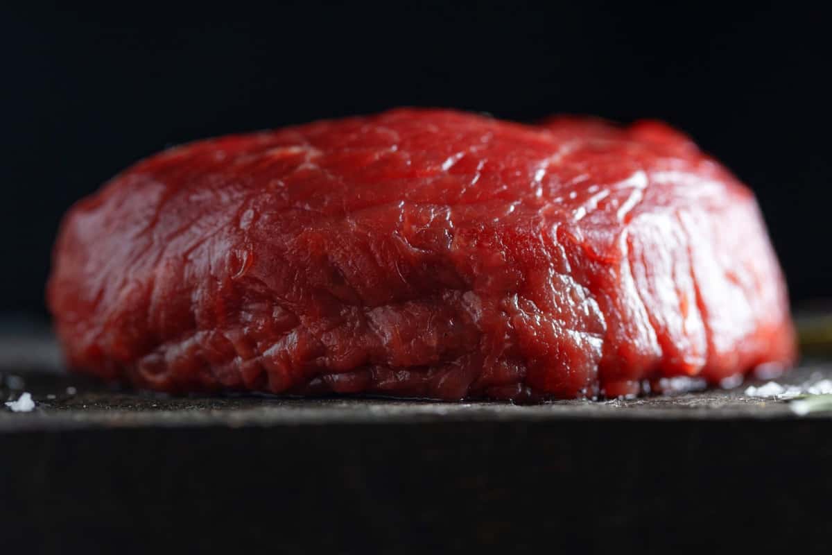 Close-up of a fresh raw beef roast on a dark board at a restaurant