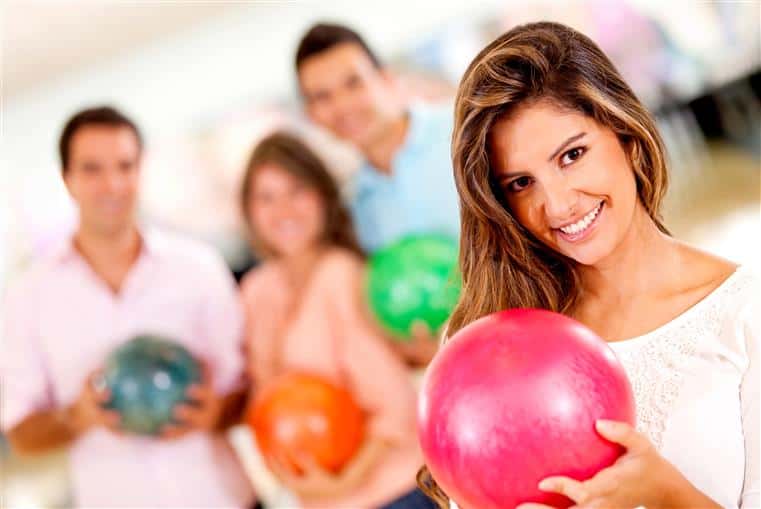 female holding bowling ball with people in the background