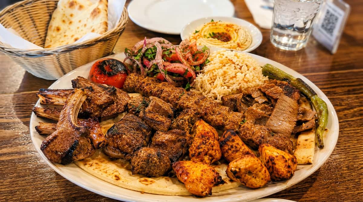 Mediterranean mixed grill platter with lamb chops, kebabs, chicken skewers, rice, grilled vegetables, and pita bread