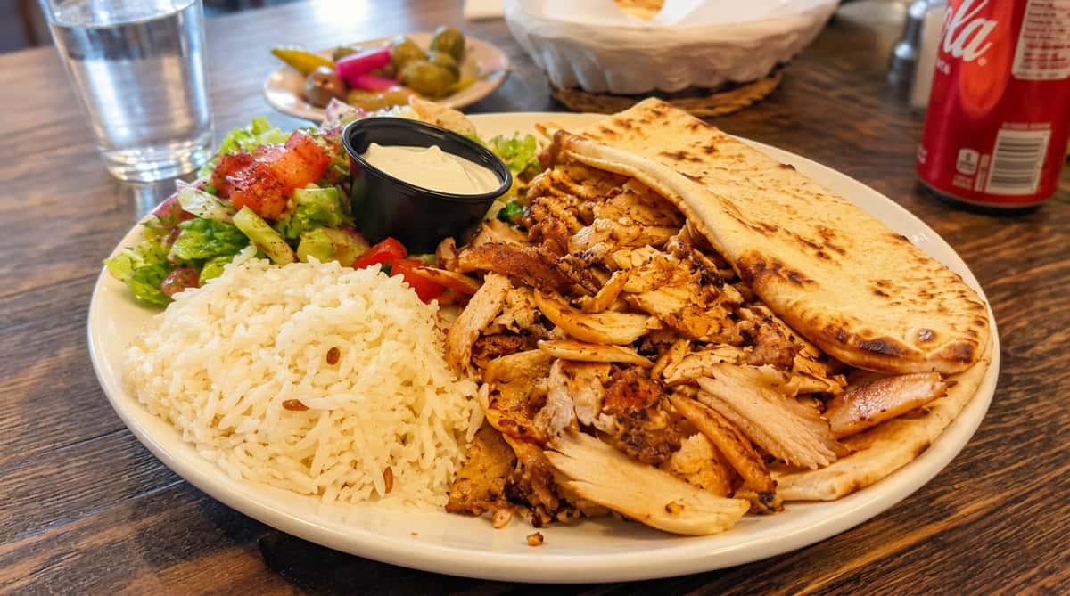 Turkish chicken döner plate with seasoned rice, fresh salad, garlic sauce, and warm pita bread