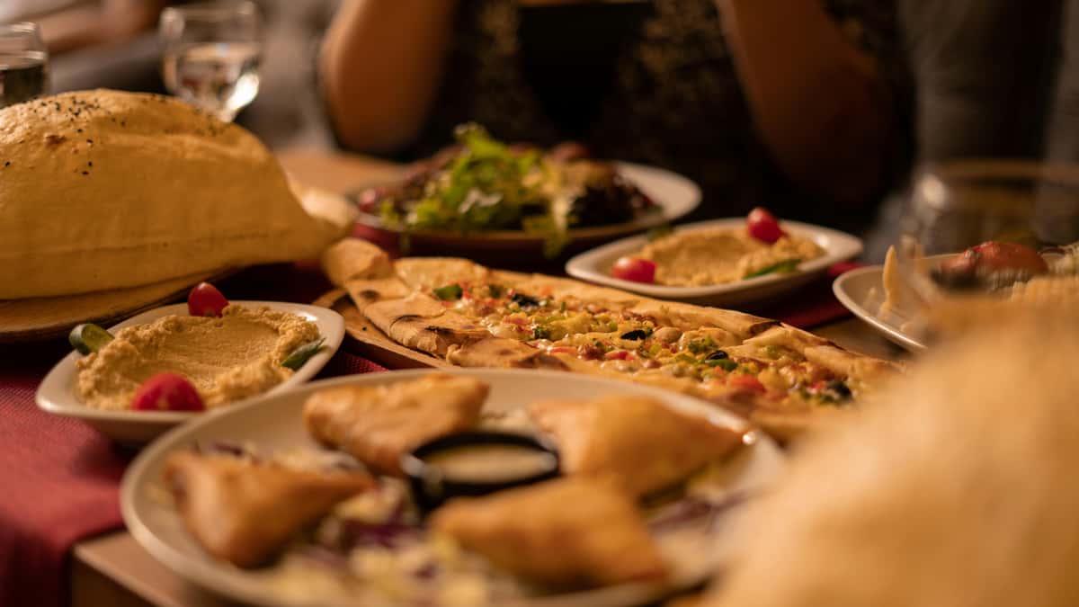 Warm Turkish dining table with hummus, flatbread, pide, and Mediterranean appetizers served in a cozy restaurant setting