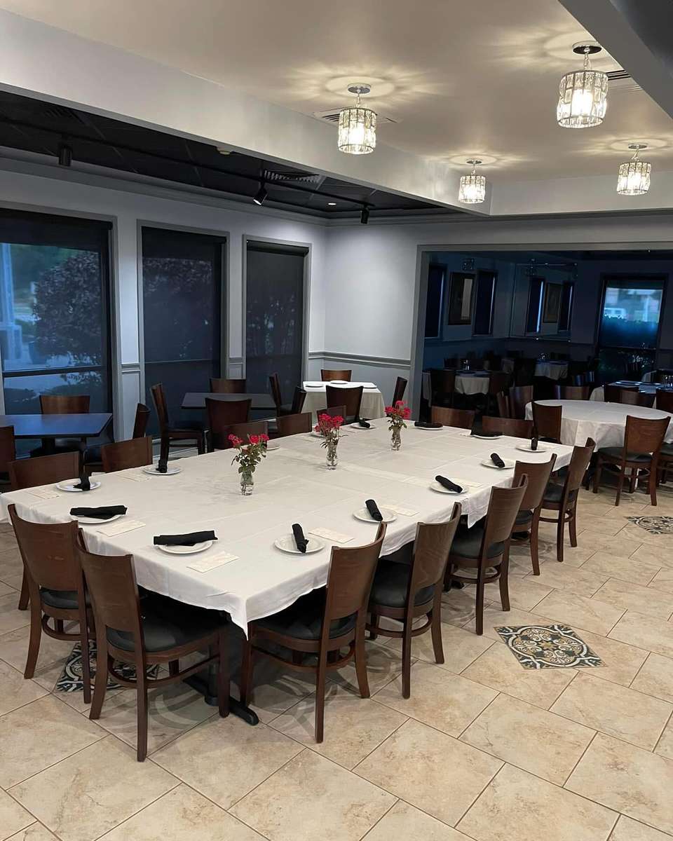 Elegant private dining room with white tablecloths, floral centerpieces, and wooden chairs set for a group gathering.