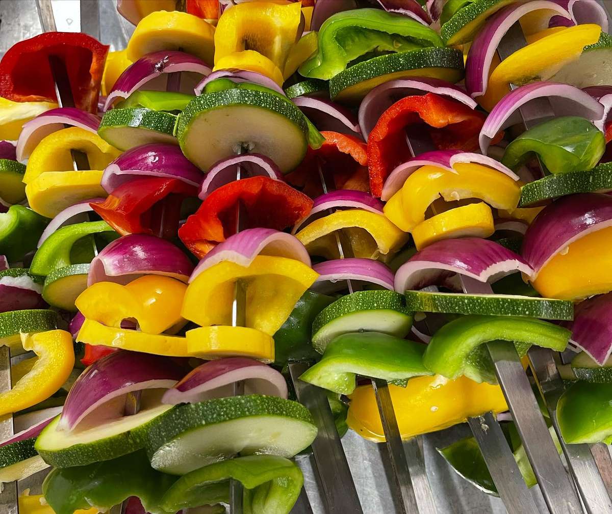 Colorful vegetable skewers with zucchini, red onions, and bell peppers, prepped for grilling at a Mediterranean restaurant.