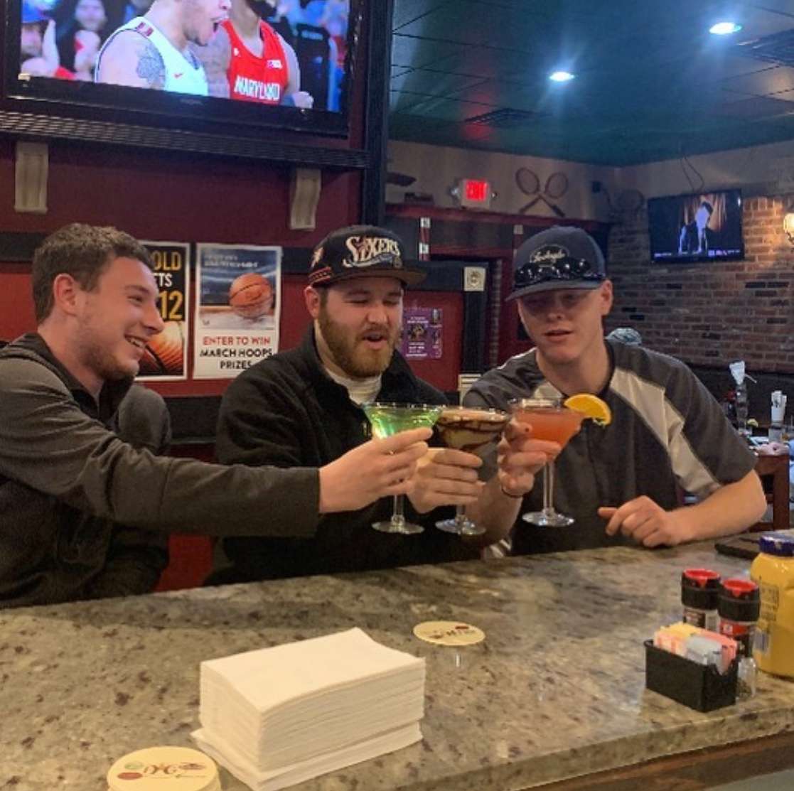 men toasting drinks at a bar