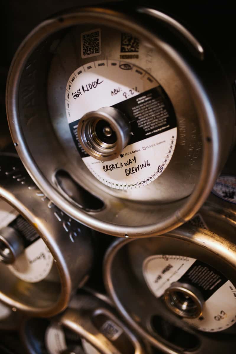 Stacked beer kegs labeled "Breakaway Brewing" with handwritten details including the name "Ghost Rider" and an ABV of 8.2%.