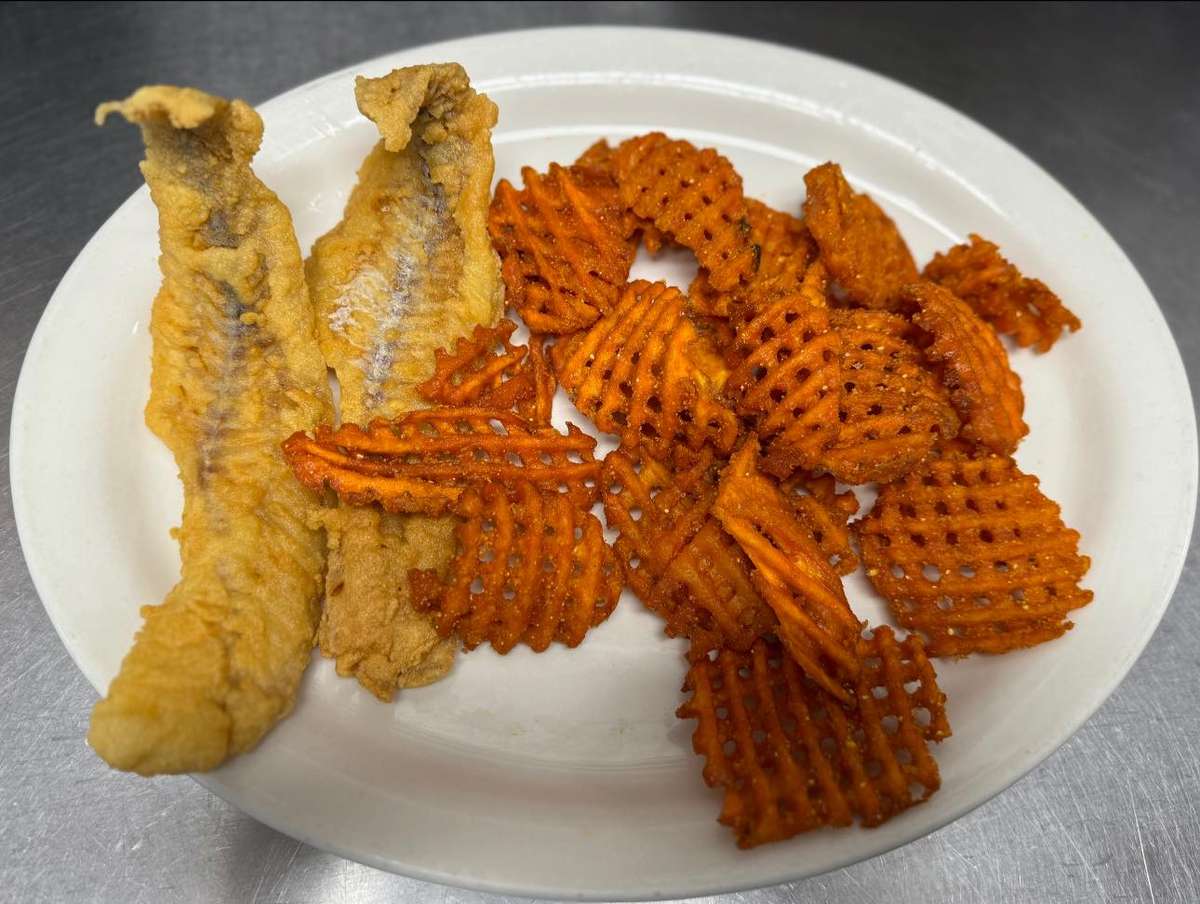 Two pieces of fried catfish served with seasoned sweet potato waffle fries on a white plate.