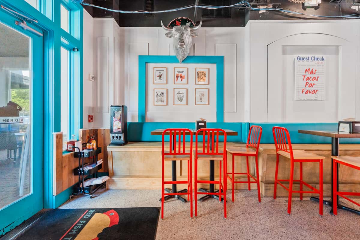 Bright and colorful restaurant dining area with turquoise walls and red seating.