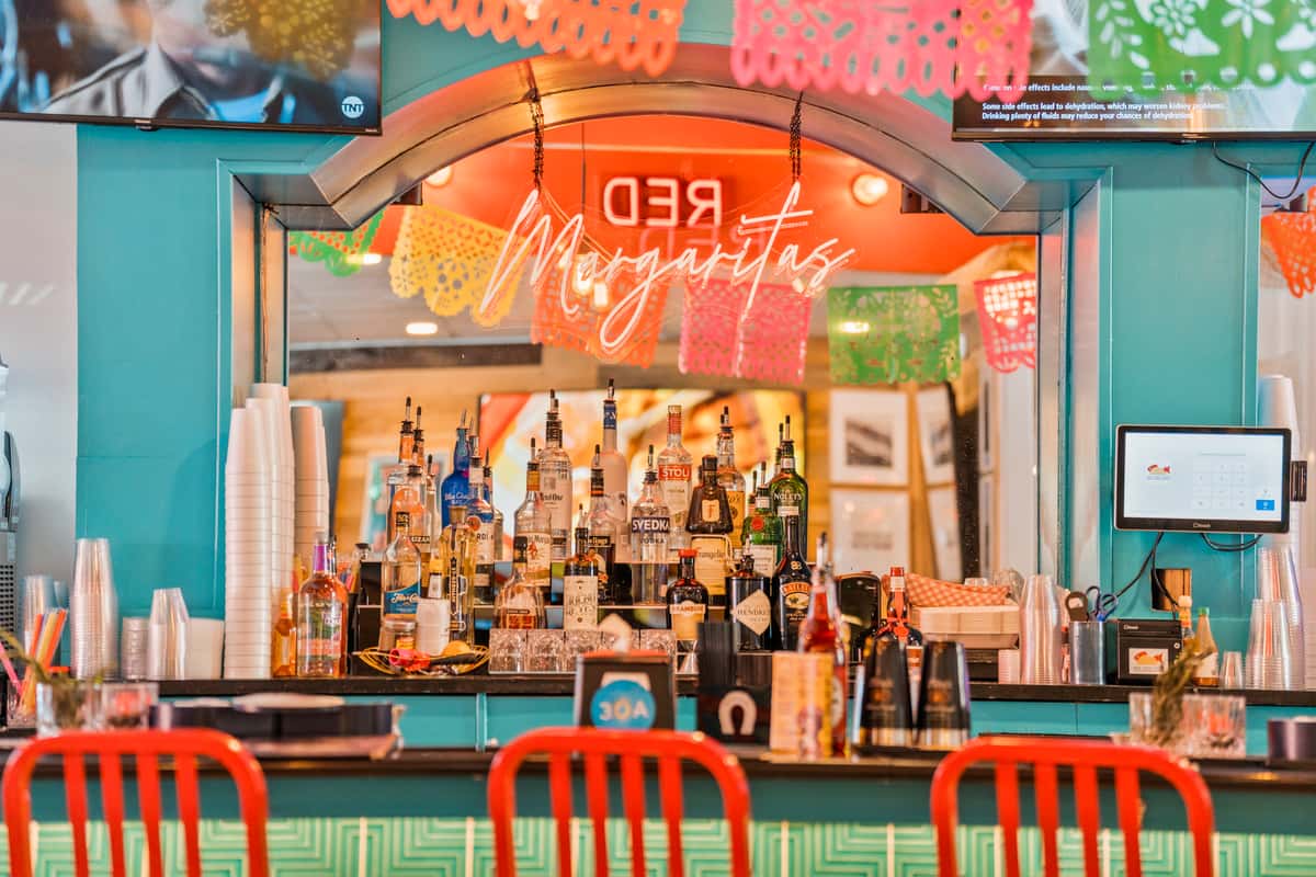 Bar area featuring liquor displays, neon signage, and vibrant décor.