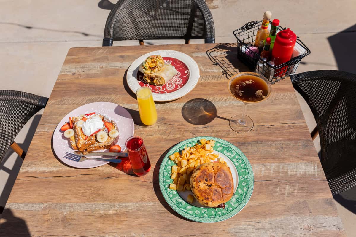 An overhead shot of a wooden table set with waffles, eggs, and orange juice.