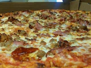 pizza topped with beef, ham and pepperoni