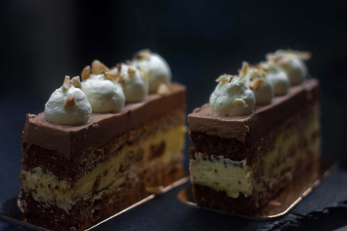 Indulgent chocolate mousse cake slices topped with whipped cream and nuts.