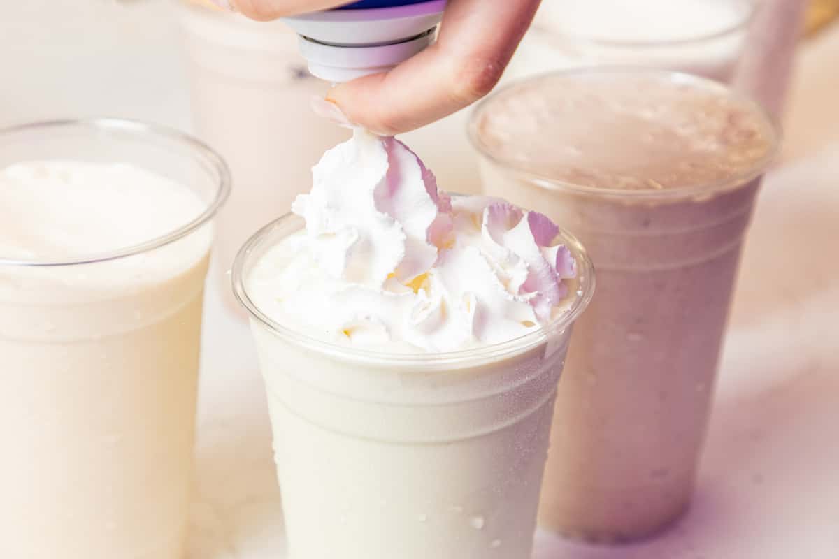 milkshake being topped with whipped cream
