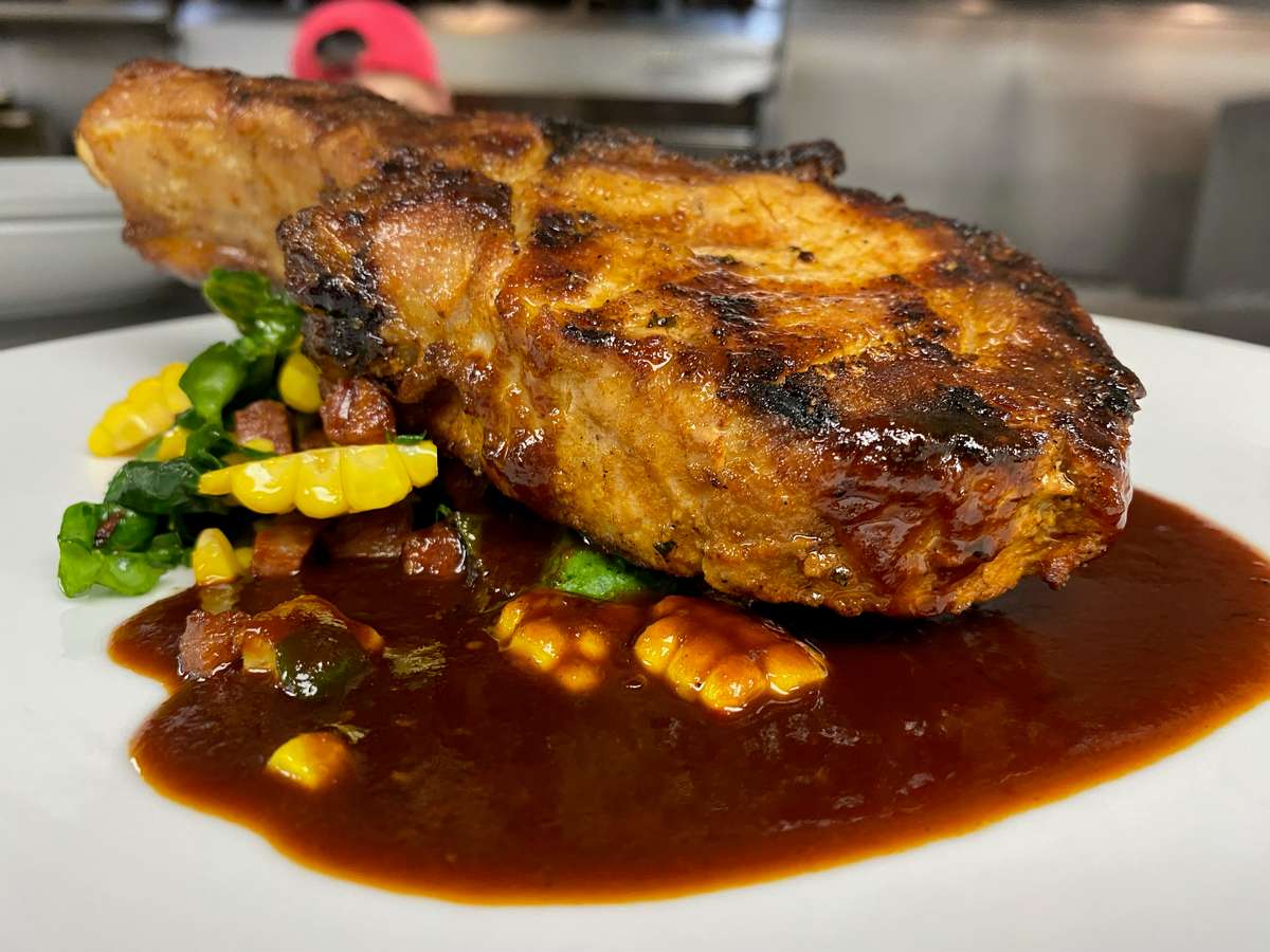 Grilled fish fillet with a golden, herb-seasoned crust, served over vegetables with a rich savoury