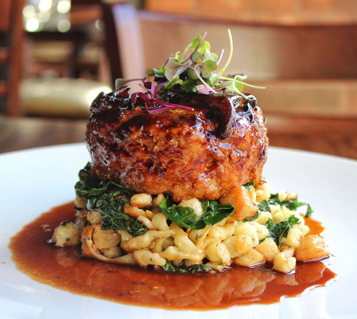 Seared fish fillet topped with fresh greens, served over vegetables and grains with a rich savoury sauce.