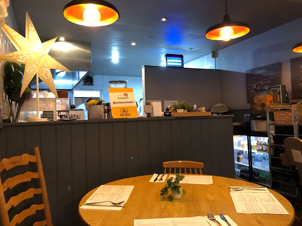 Restaurant seating area with a wooden table, booth seating, and pendant lights