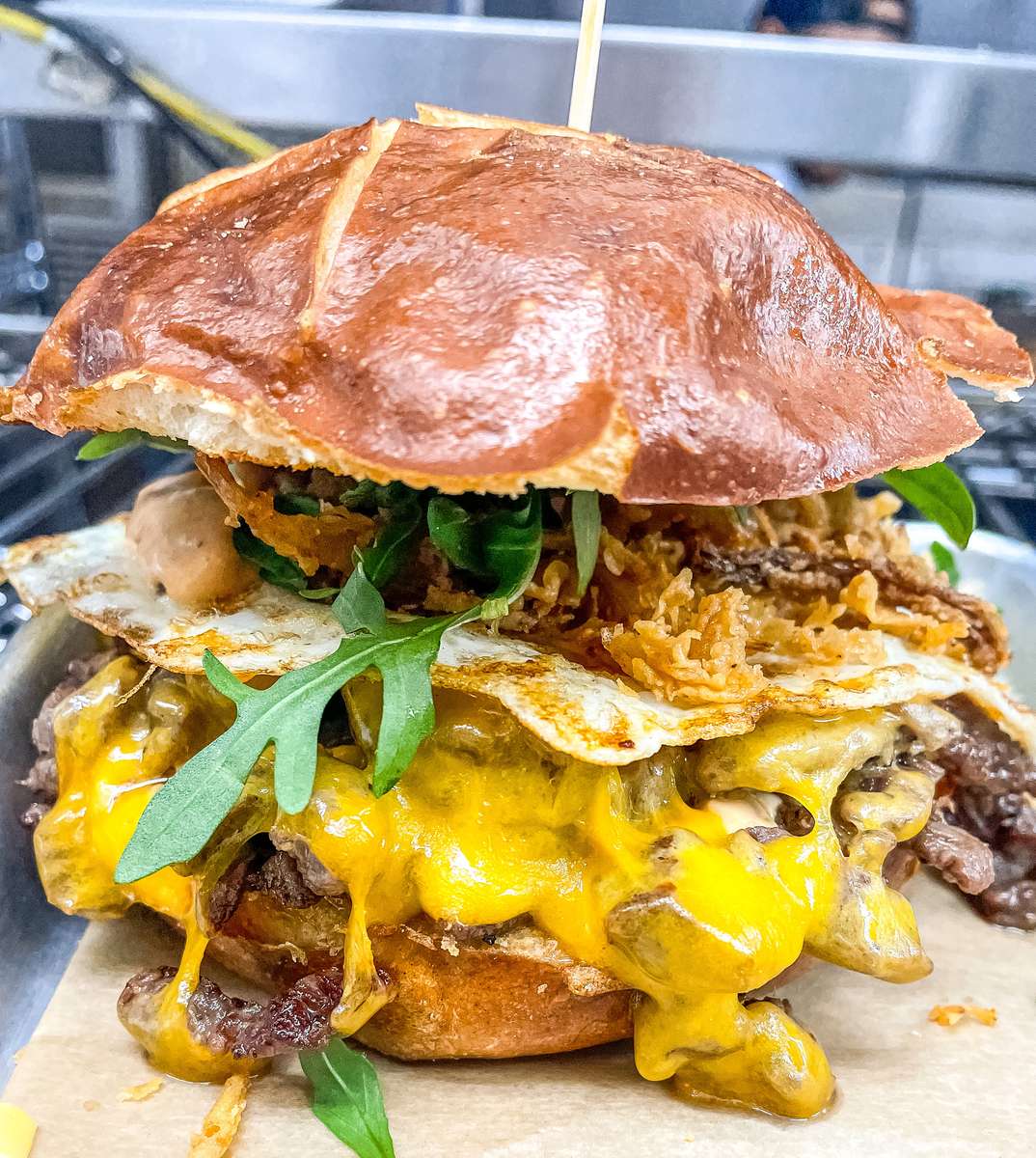 Smoked brisket with a fried egg, cheddar cheese, chipotle mayo, crispy onions & arugula on a toasted pretzel bun.