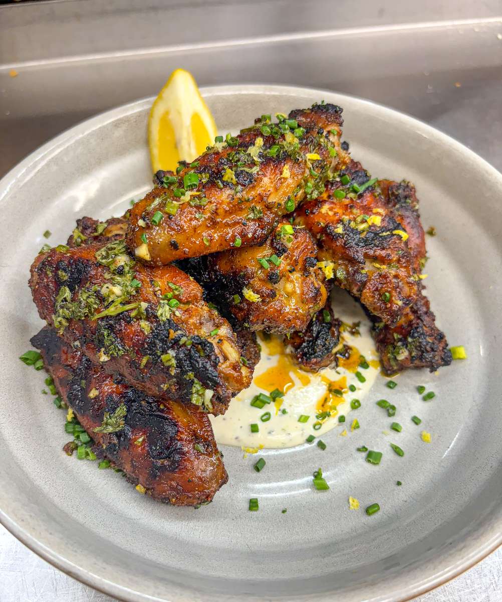 Grilled Greek Wings tossed with homemade garlic-lemon-herb sauce served over feta ranch.