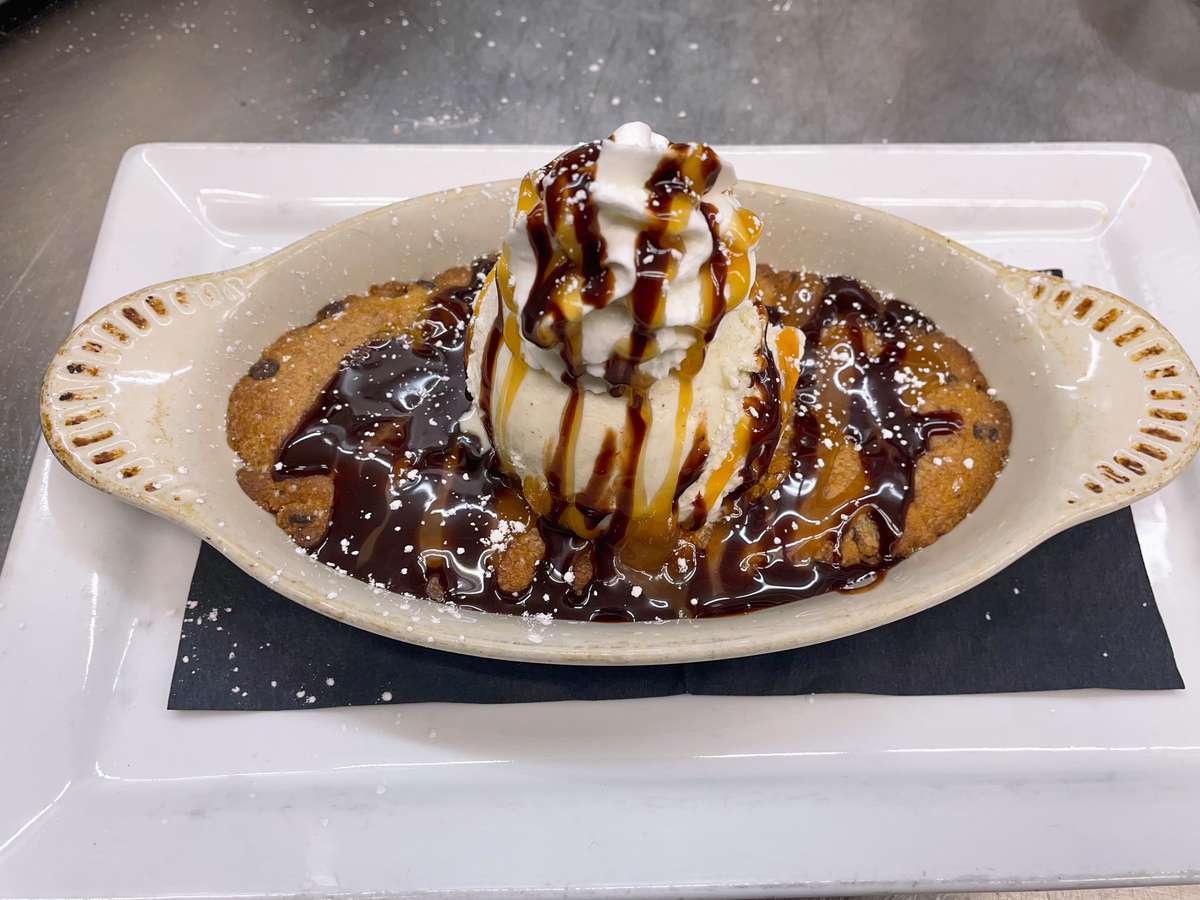 Fresh baked brown butter cookie skillet with caramel and chocolate sauce.