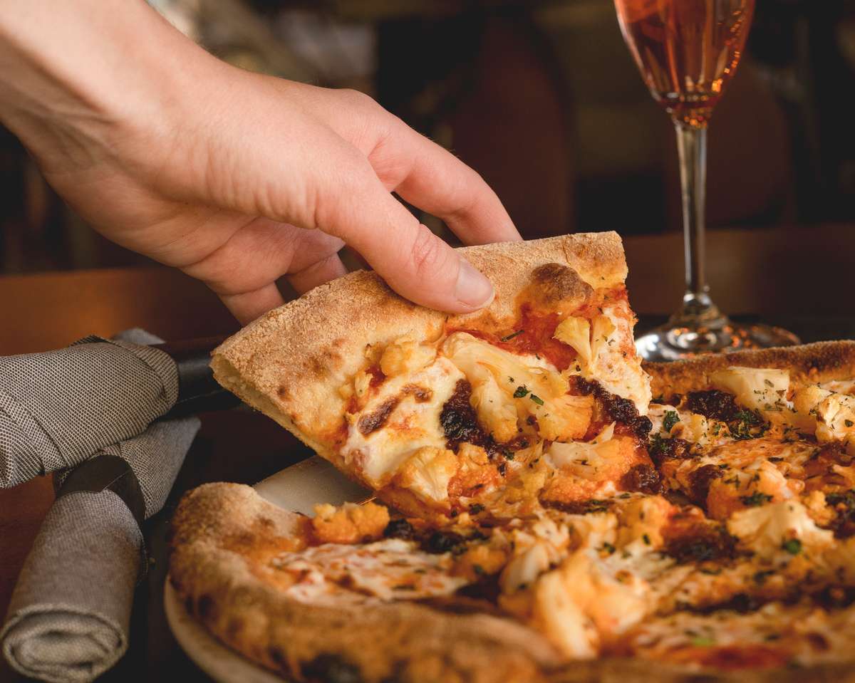 Pizza piece being picked up by customer