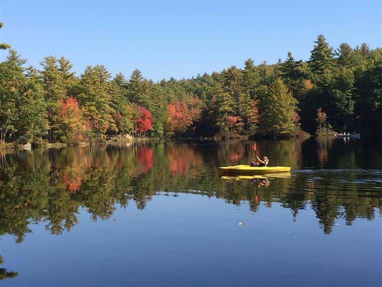 large lake with a woman paddleboating in the middle of it
