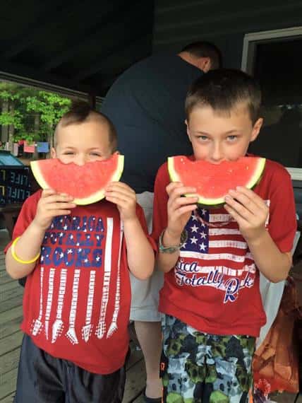two young boys eating watermelon together 