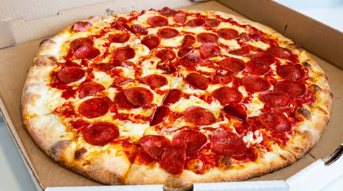 Pepperoni pizza with melted mozzarella and tomato sauce in a cardboard box.