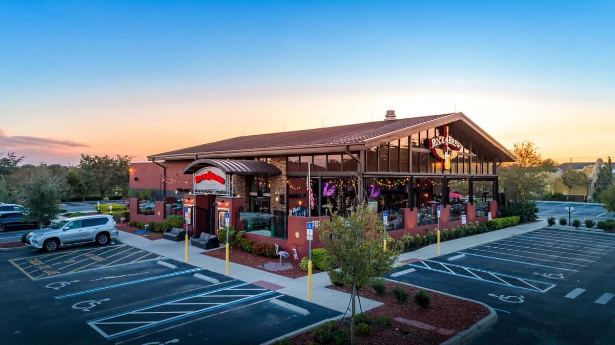 Photo shows the outside of Rock & Brews restaurant and part of their parking lot