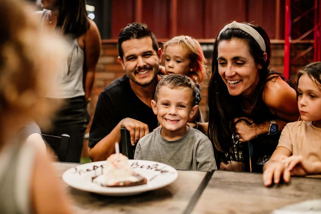 Family celebrating a child's birthday at a decorated table with balloons and a birthday cake in Oviedo, FL