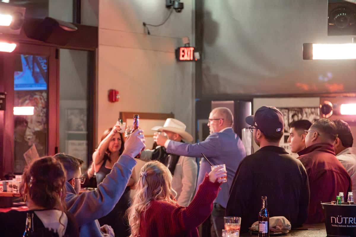 Coworkers gathered around a reserved table sharing food and drinks at a work happy-hour event in Oviedo, FL