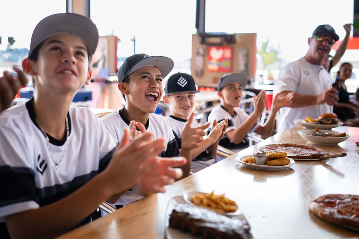 Youth sports team in matching jerseys seated together at a long table sharing a post-game meal in Oviedo, FL