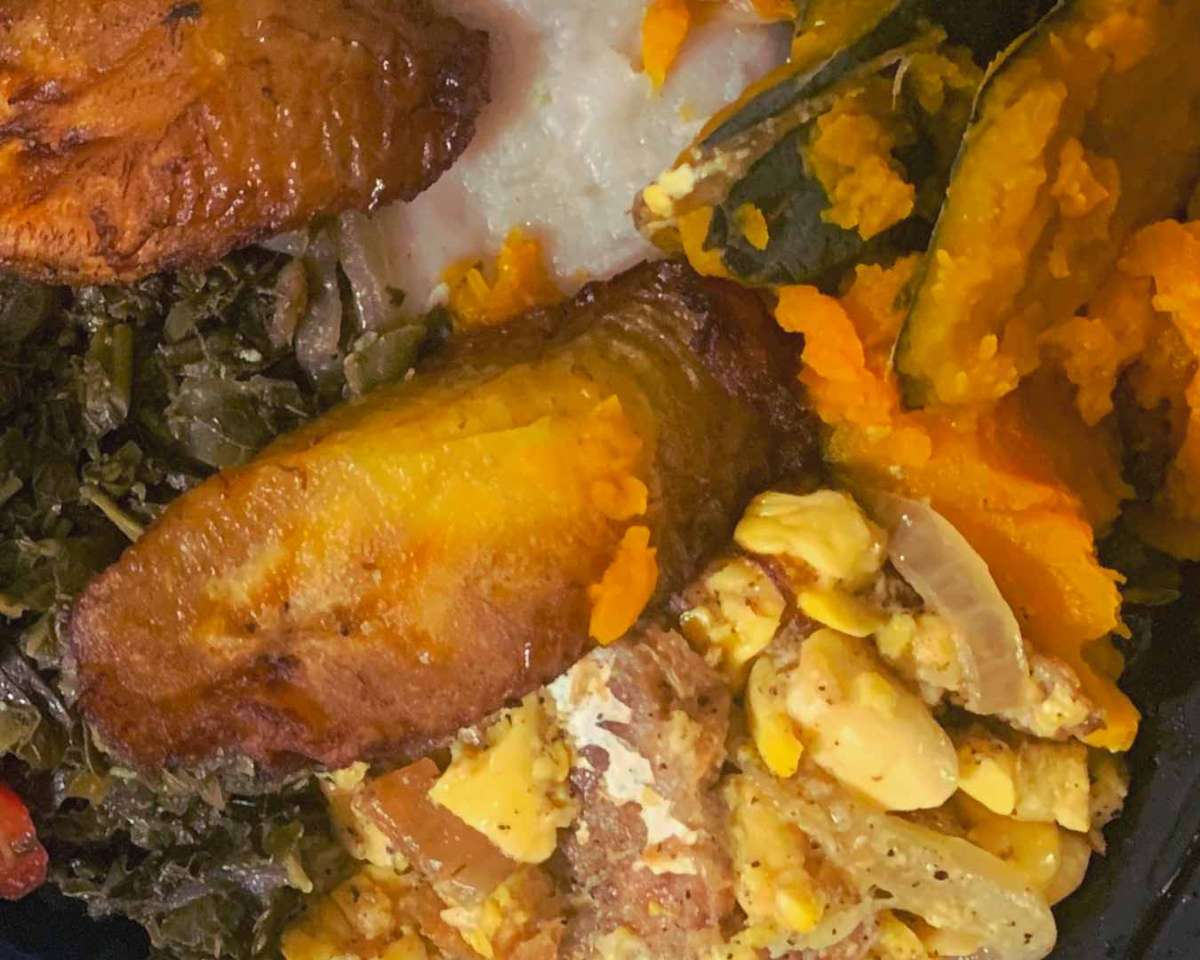 Jamaican breakfast plate with ackee and saltfish, fried plantains, steamed callaloo, boiled dumpling, and pumpkin.
