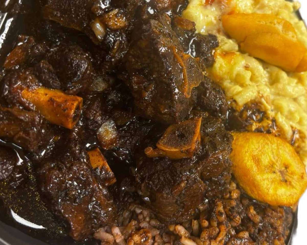 Rich Jamaican oxtail stew served over rice and peas with creamy macaroni and cheese and fried plantains.