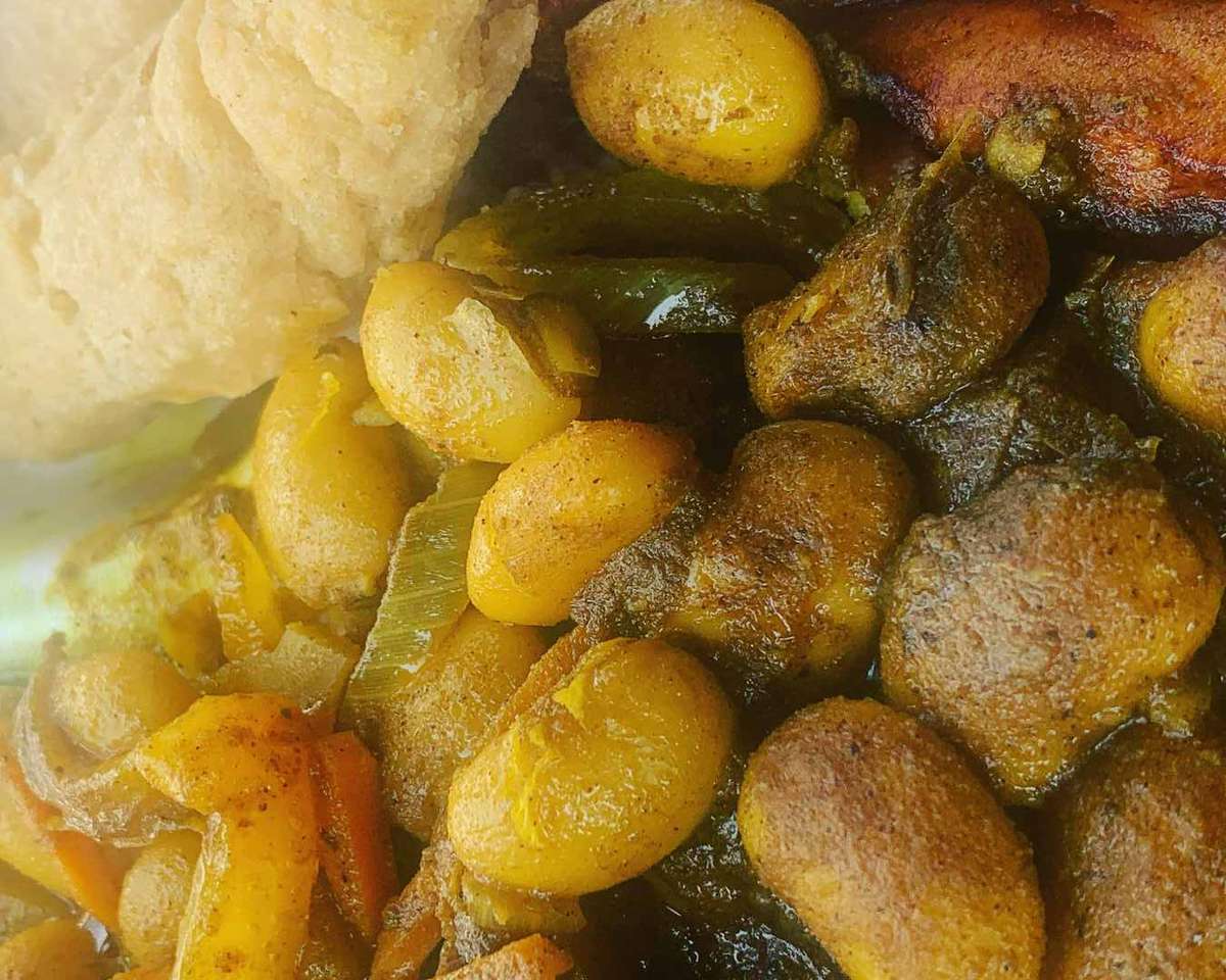 Jamaican stew peas with dumplings, butter beans, and fried plantain, served with a piece of festival dumpling.