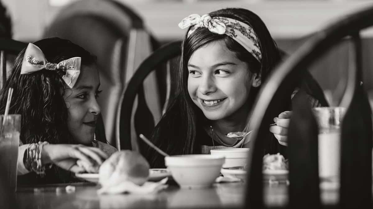 Two girls smile while eating dinner