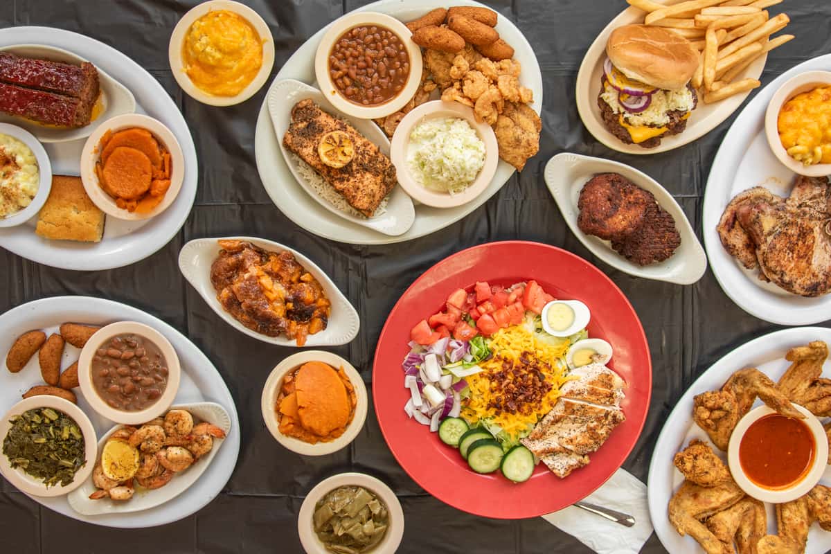 A variety of plates and bowls filled with comfort food on a black table cloth