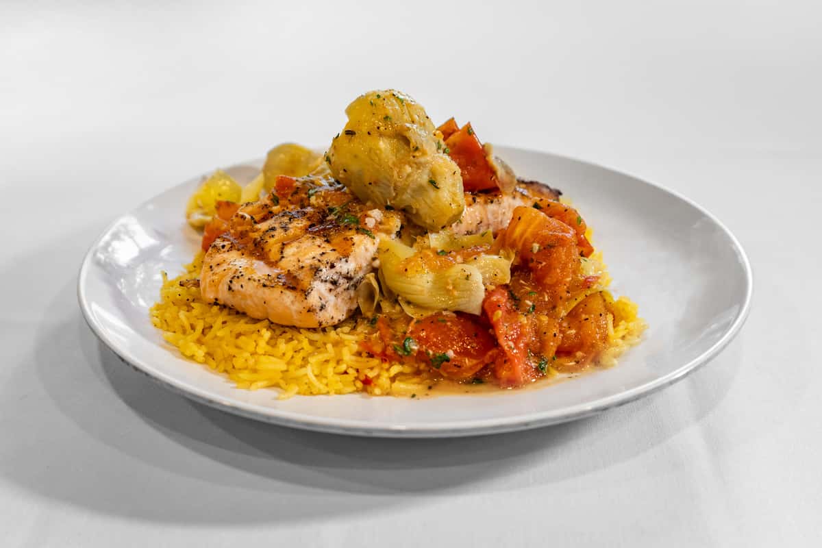 Salmon filet grilled to perfection, served over house basmati rice, and topped with sauteed artichokes and roasted Roma tomatoes with a citrus butter sauce.
