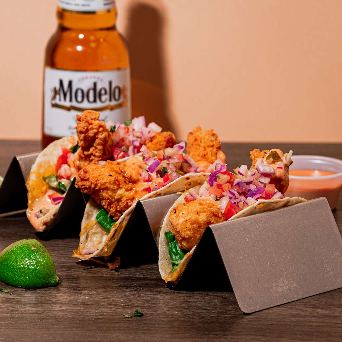 Three soft corn tacos with fried chicken, topped with fresh pico de gallo