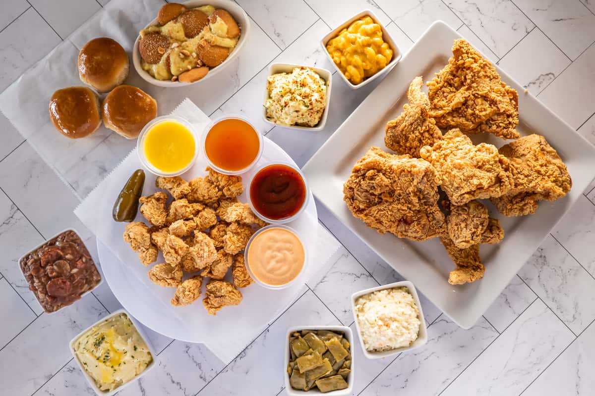 Southern-style fried chicken platter with crispy wings, chicken bites, dipping sauces, mac and cheese, and classic comfort food sides