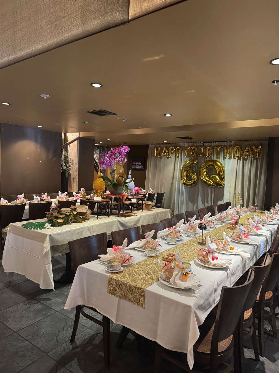 private dining room setup with long banquet table, elegant place settings, and gold birthday balloons for celebration at Thai restaurant