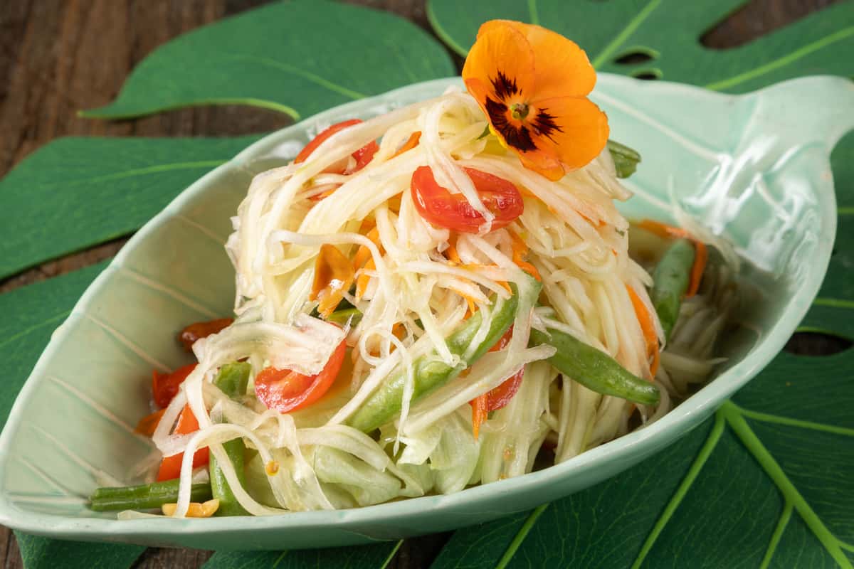 Fresh Thai papaya salad tossed with crisp vegetables, herbs, and zesty dressing, delivering a refreshing balance of sweet, tangy, and spicy authentic Thai flavor.