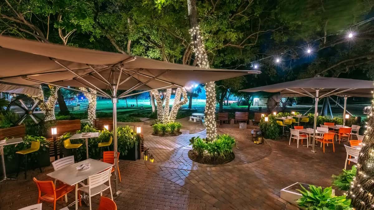 Exterior view of Glass & Vine restaurant's lush outdoor dining area in Peacock Park