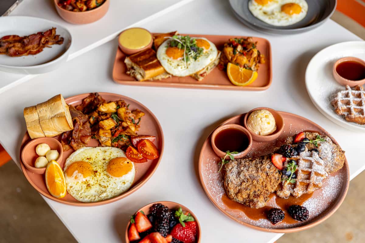 Brunch plates with eggs, waffles, berries, and breakfast sides at Glass & Vine