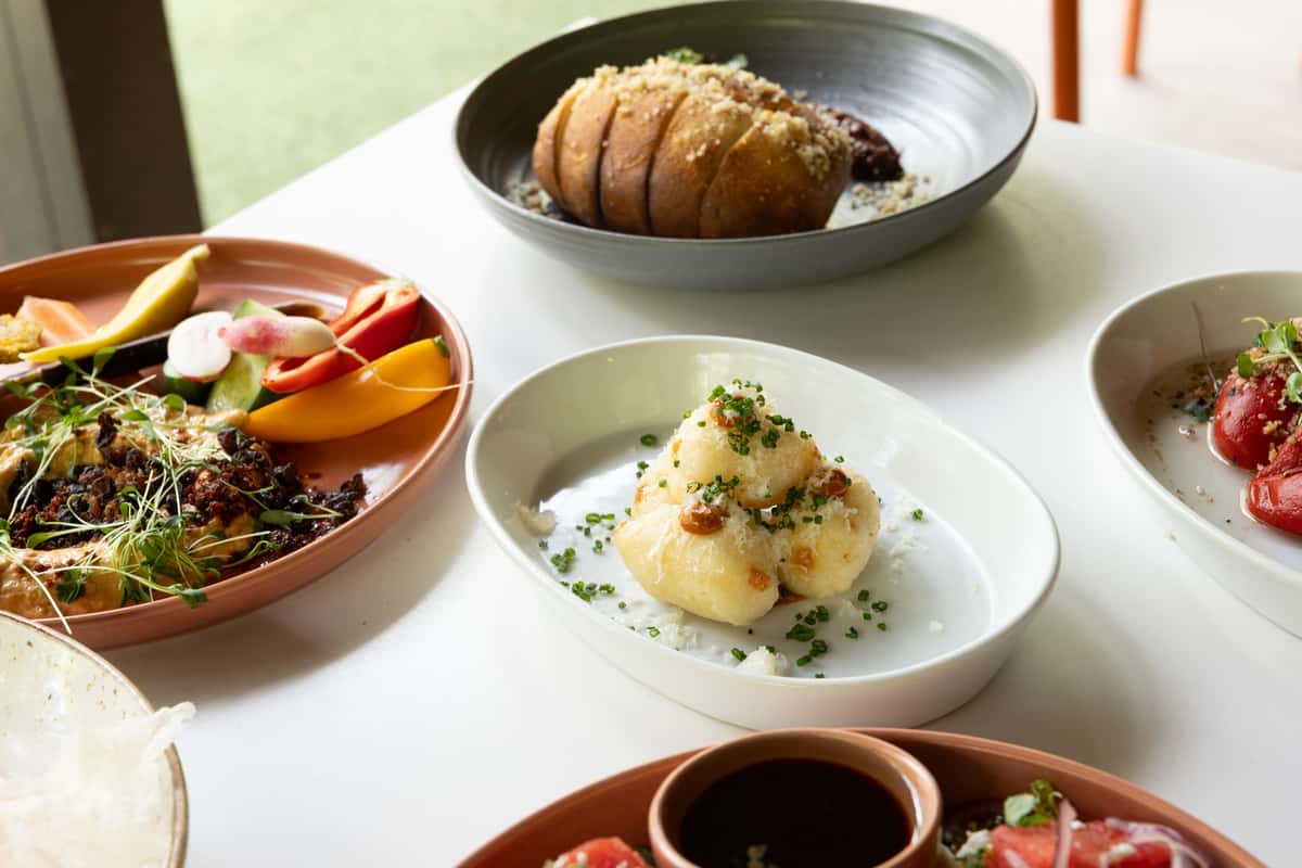 Glass & Vine brunch spread with roasted vegetables, bread, tomatoes, and plated small dishes