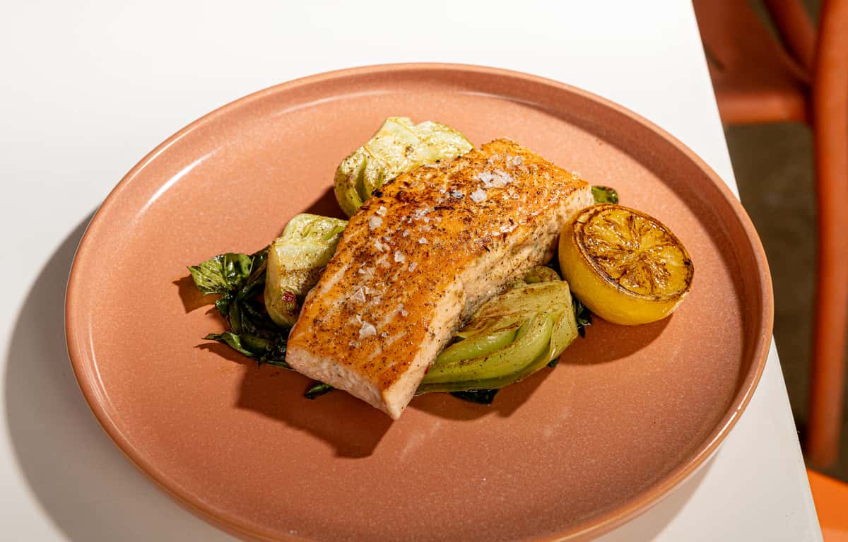 Grilled salmon with vegetables and charred lemon served as a balanced wellness-focused dish